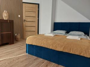1 dormitorio con 1 cama azul y suelo de madera en Dom wakacyjny Małe Swornegacie nad trzema jeziorami, en Małe Swornigacie