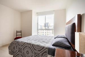 ein Schlafzimmer mit einem Bett und einem großen Fenster in der Unterkunft Apartment, renovated perfect for Nomads in Mexiko-Stadt