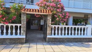 a house with a white fence and pink flowers at Beachfront apartment 10m from the beach in Paralia Dionysiou