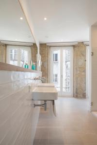 uma casa de banho branca com 2 lavatórios e janelas em Porto Real Hotel em Finisterre