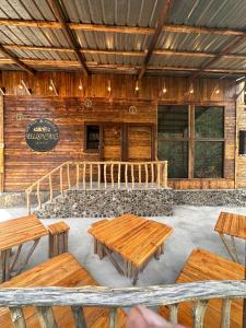 ein Holzgebäude mit Holztischen und Bänken in der Unterkunft MELQONYAN'S Guest House & Coffee in Tʼumanyan