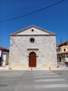 a stone building with a brown door and a window at Valaoritou Apartment in Lefkada