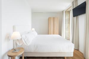 a bedroom with a white bed and a table with a lamp at Porto Real Hotel in Finisterre
