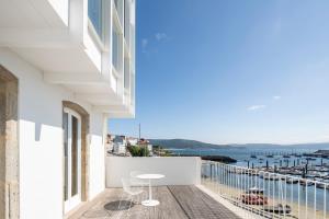 balcón con mesa, sillas y vistas al océano en Porto Real Hotel, en Finisterre