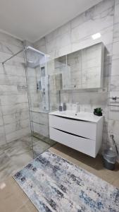 a white bathroom with a sink and a shower at Apartman Silver in Bugojno