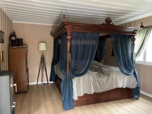 a bedroom with a canopy bed with blue curtains at Hadeland Cottage in Lunner