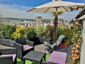 a patio with chairs and an umbrella on a balcony at DERNIER ETAGE TERRASSE Pte St Coud in Boulogne-Billancourt