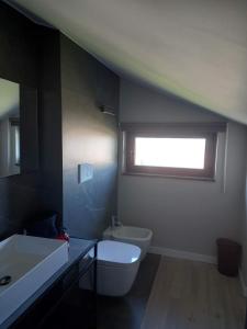 uma casa de banho com um WC, um lavatório e uma janela em Live Attic room em Somma Vesuviana