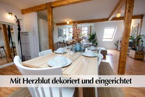 ein Esszimmer mit einem Holztisch und weißen Stühlen in der Unterkunft Helles 80m2 Maisonette-Loft mit Balkon, Kingsize Bett, Smart-TV, etc in Erfurt