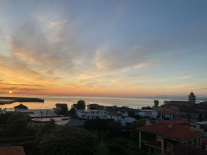 una vista de una ciudad con una puesta de sol en el fondo en La Casa del Gallo, en Luanco