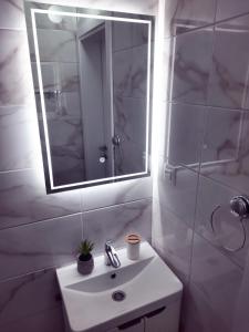 W białej łazience znajduje się umywalka i lustro. w obiekcie Cozy apartment close to Dubrovnik w Neum