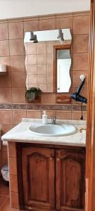 uma casa de banho com um lavatório e um espelho em Habitación matrimonial en un bajo baño compartido Areas compartidas em Abades