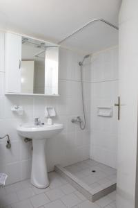 a white bathroom with a sink and a shower at Mary's Studios in Agia Pelagia