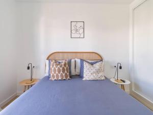 um quarto com uma cama com lençóis e almofadas azuis em Apartamento Dara - Apartamento con piscina em Tías