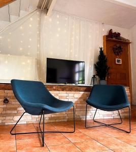 2 blaue Stühle in einem Wohnzimmer mit einem TV in der Unterkunft Agro - Dom Wsrod Lasow in Trzcianka