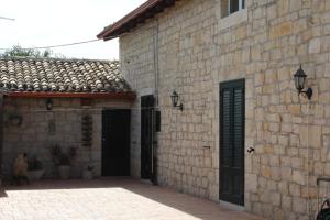 a stone building with two doors and a courtyard at Appartamento Le Tre Palme in Frigintini
