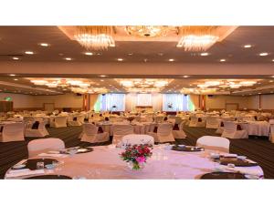 un gran salón de banquetes con mesas blancas y sillas blancas en Hotel Satsukien - Vacation STAY 75955v en Kanoya