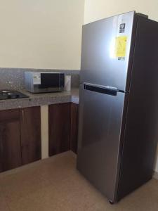 una nevera de acero inoxidable en una cocina junto a un microondas en Agradable casa de campo con estacionamiento, en Olón