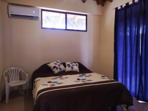 1 dormitorio con 1 cama con cortinas azules y ventana en Agradable casa de campo con estacionamiento, en Olón