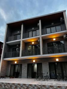 an apartment building with a balcony and tables and chairs at Sunrise Ureki in Ureki