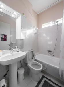 een witte badkamer met een wastafel, een toilet en een bad bij Lacustris in Ioannina