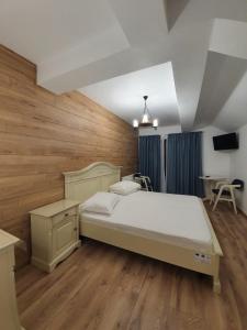 a bedroom with a large bed and wooden floors at Pensiunea Iasmina si Pescarul in Călimăneşti