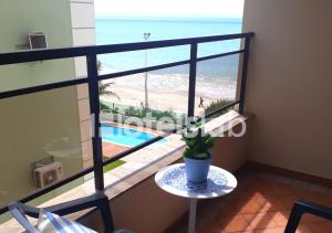 Cette chambre dispose d'une table et offre une vue sur la plage. dans l'établissement Lindo apartamento com vista para o mar em Canasvieiras C108, à Florianópolis