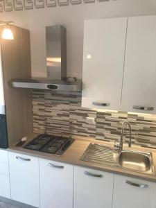 cocina con armarios blancos, fregadero y fogones en Premium apartment with parking, en Ciampino