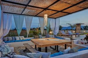 a patio with a wooden table and couches at Villa Arianna, close to the beach! in Kalamaki