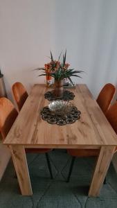 a wooden table with a vase of flowers on it at Apartman Orange in Bugojno