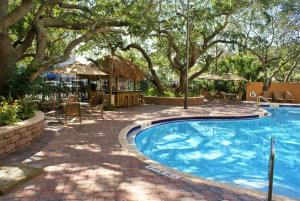 a swimming pool with a patio and trees at Courtyard by Marriott Cocoa Beach Cape Canaveral in Cocoa Beach