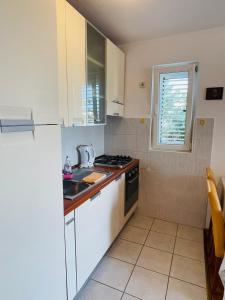 cocina con armarios blancos, fogones y ventana en Peace Sea View Apartment, en Makarska