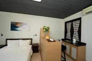 a bedroom with a bed and a desk and a window at Dana Pearl Riverside Condotel in Danang