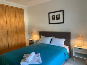 Un dormitorio con una cama azul con toallas. en Vista das Ondas - AP, en Albufeira