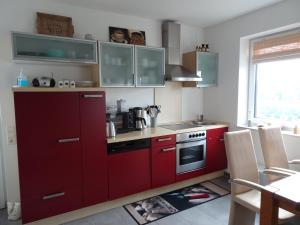 een keuken met rode kasten en een rode kachel bij Ferienwohnung Büren-Harth in Büren