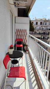Un balcón con 2 sillas rojas y una mesa. en Think Home, exploring the center of Thessaloniki en Tesalónica