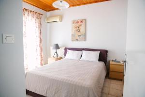 1 dormitorio con cama blanca y ventana en Nous Dios en Xilokéra