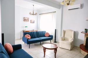 een woonkamer met een blauwe bank en 2 stoelen bij Nous Dios in Xilokéra