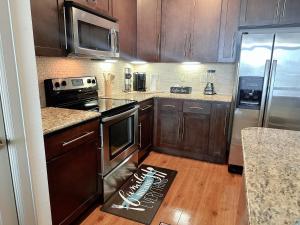 una cocina con armarios de madera y electrodomésticos de acero inoxidable en Domain at Kirby en Houston