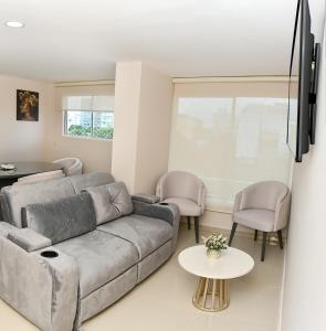 uma sala de estar com um sofá cinzento e cadeiras em De estreno, nuevo apto en Barranquilla em Barranquilla