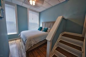 a bedroom with a bed with blue walls and a staircase at Turner's loft / sleeps 4 in the heart of the town in Wilmington