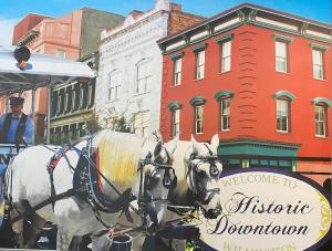 dos caballos tirando de un carruaje en una calle de la ciudad en Turner's loft / sleeps 4 in the heart of the town en Wilmington