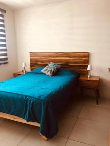 a bedroom with a bed with blue sheets and two tables at Be Central Departamento con alberca en el centro de Guadalaja in Guadalajara