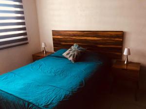 a bedroom with a blue bed with a wooden headboard at Be Central Departamento con alberca en el centro de Guadalaja in Guadalajara