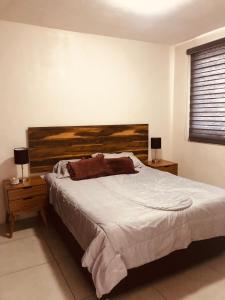 a bedroom with a large bed with a wooden headboard at Be Central Departamento con alberca en el centro de Guadalaja in Guadalajara