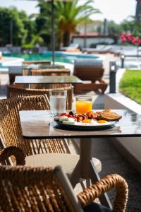 a table with a plate of food and orange juice at domus hospitality in Vourvourou