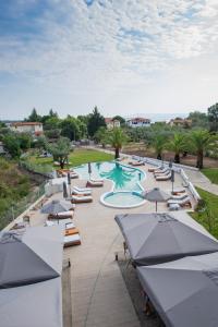 a pool with lounge chairs and umbrellas in a resort at domus hospitality in Vourvourou