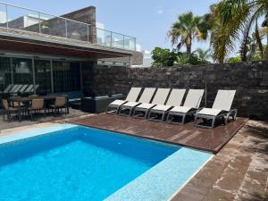 una piscina con sedie a sdraio e una casa di Exclusive Villa in Bahia del Duque ad Adeje