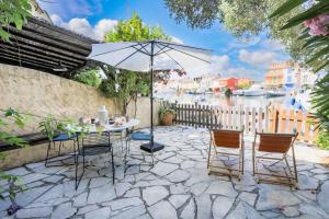 a patio with a table and chairs and an umbrella at Appartement « AMOUR » luxueux avec amarrage 11m in Grimaud