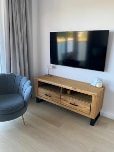 a living room with a television and a blue chair at Apartament Coral in Grzybowo
